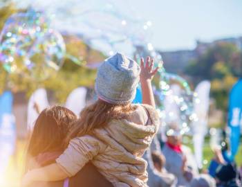 A woman holding a little girl while bubbles float in the background
