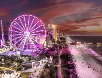Aerial overview of the Myrtle Beach Boardwalk and Myrtle Beach SkyWheel with pink neon lights