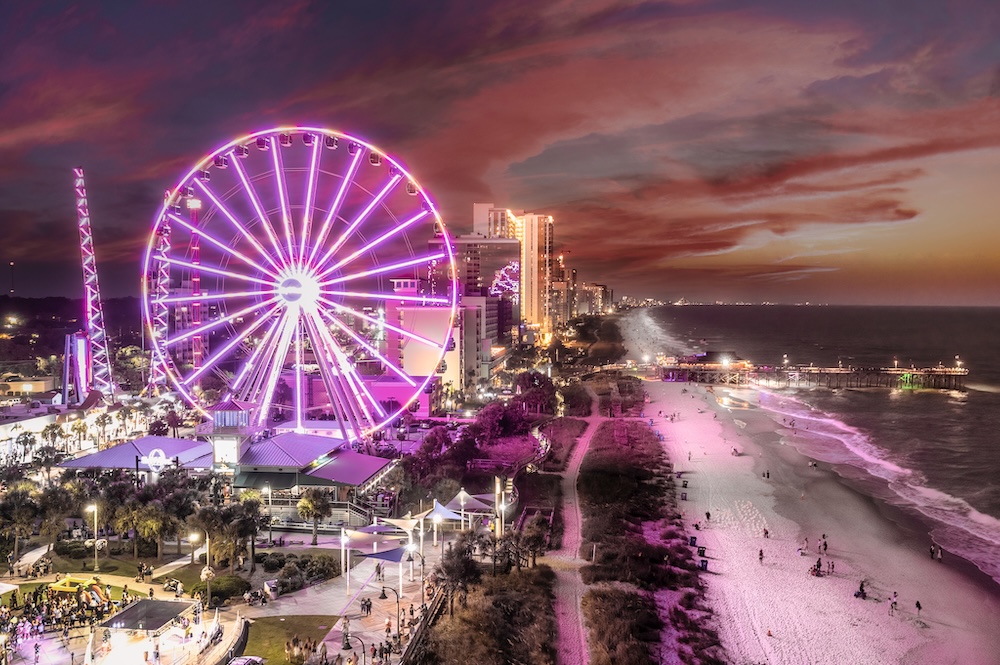 Aerial overview of the Myrtle Beach Boardwalk and Myrtle Beach SkyWheel with pink neon lights