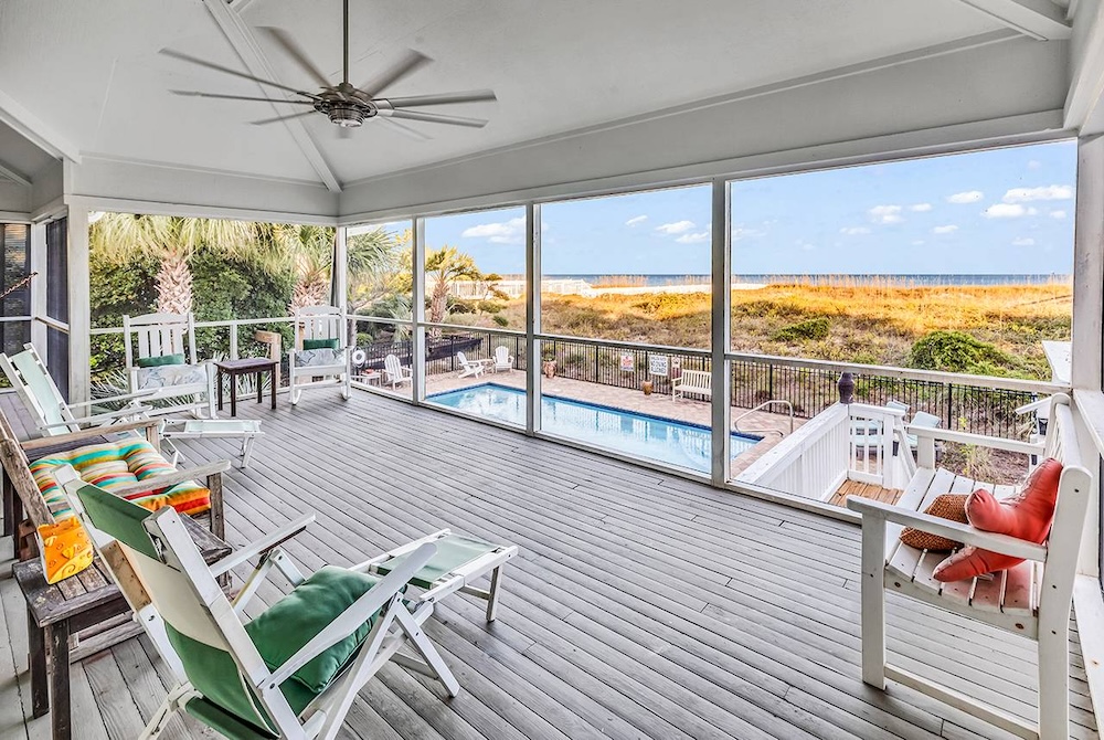 Vacation rental screened porch with pool and ocean view in background