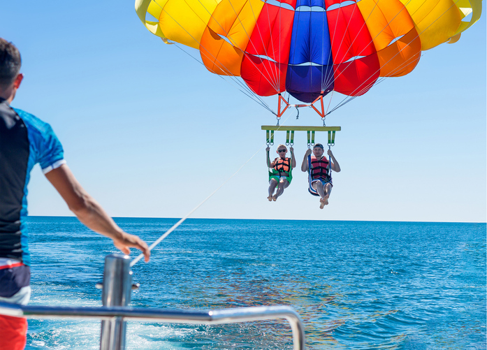 A pair parasailing over the water