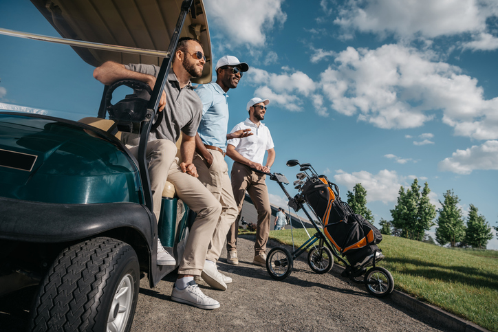 A group of friends watch a fellow golfer swing