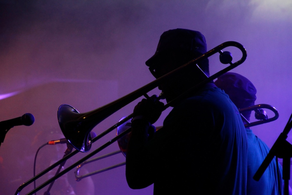 A musician playing a trombone with smoke and purple lighting in the background
