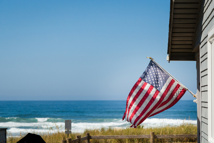 An American flag flying above an oceanfront property