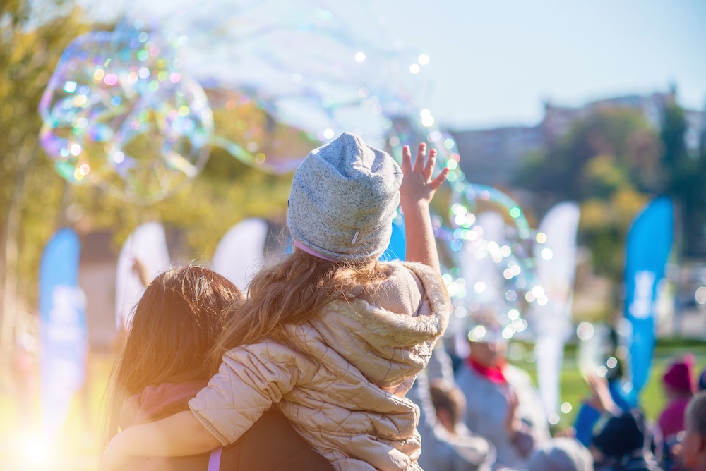 A woman holding a little girl while bubbles float in the background